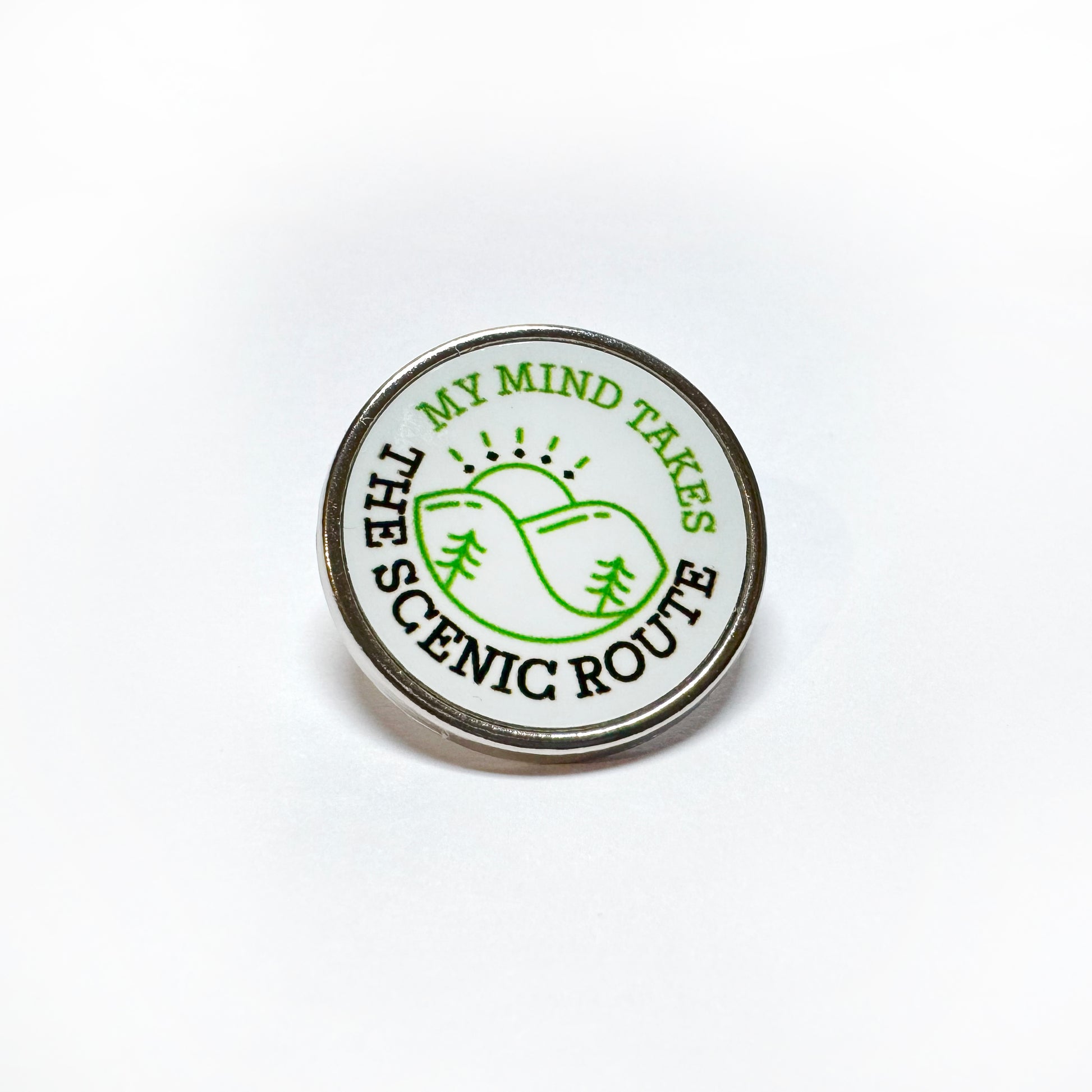 Badge with a green hill which reads My mind takes the scenic route"