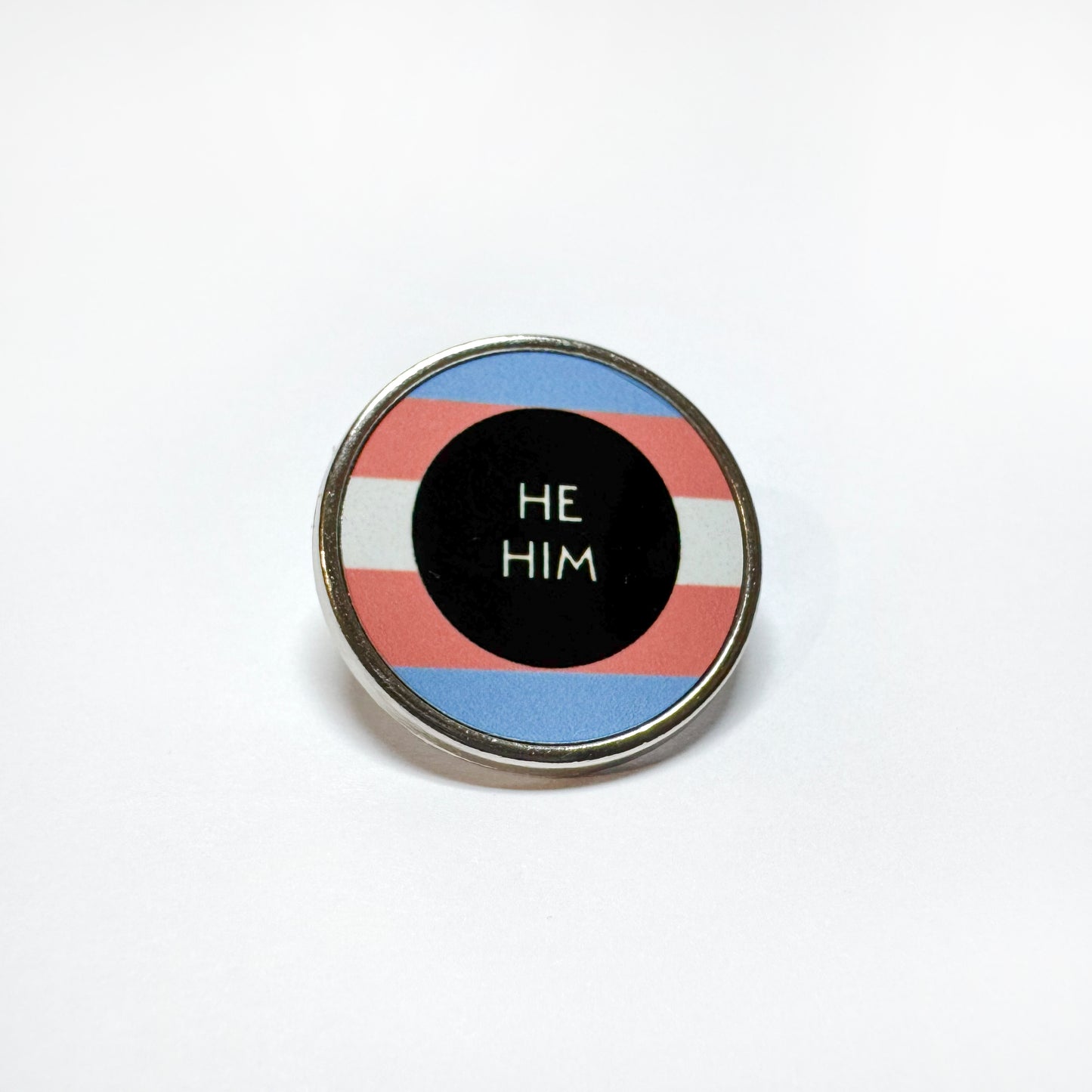 Trans flag badge which reads he him